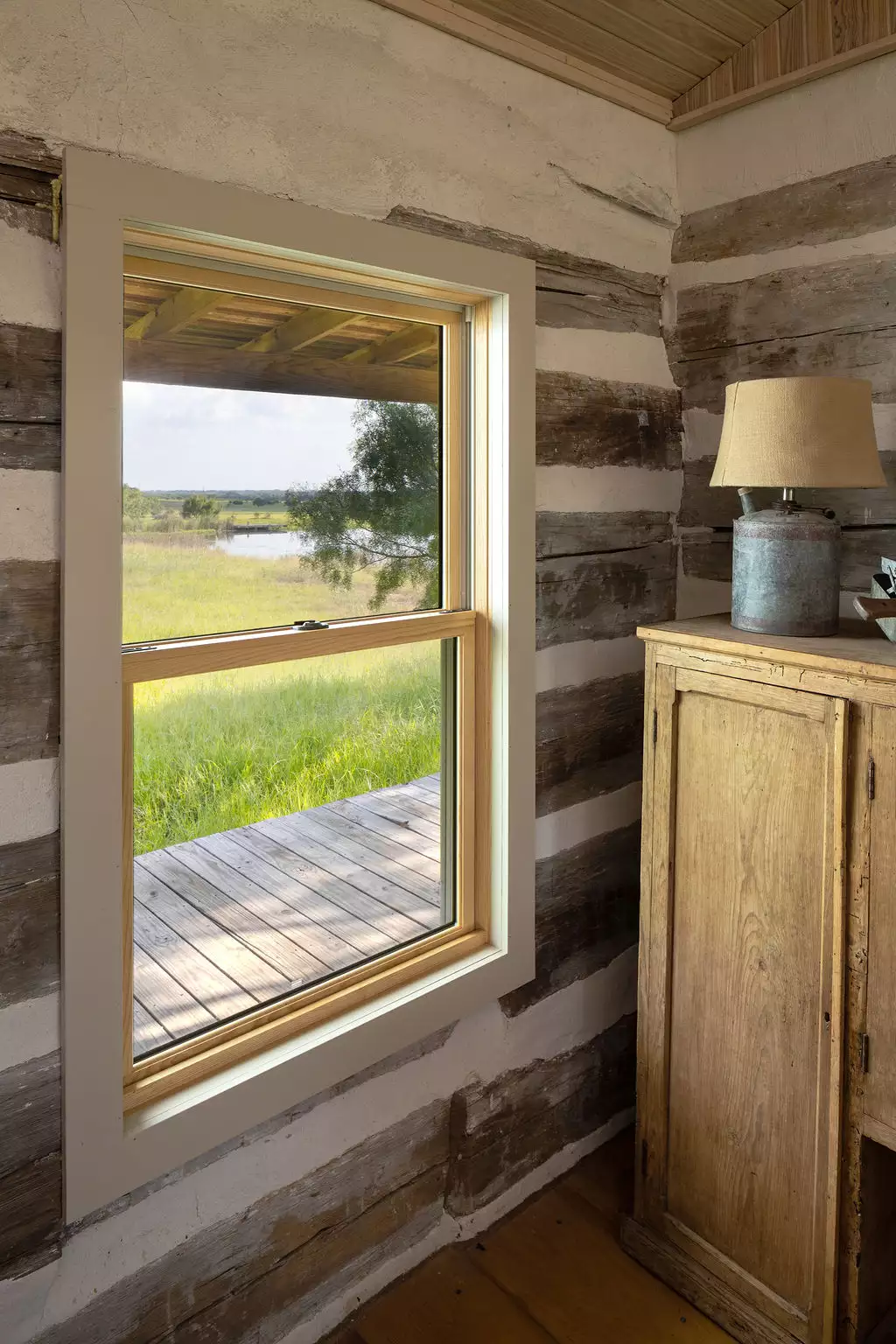 log cabin side window with dresser and lamp